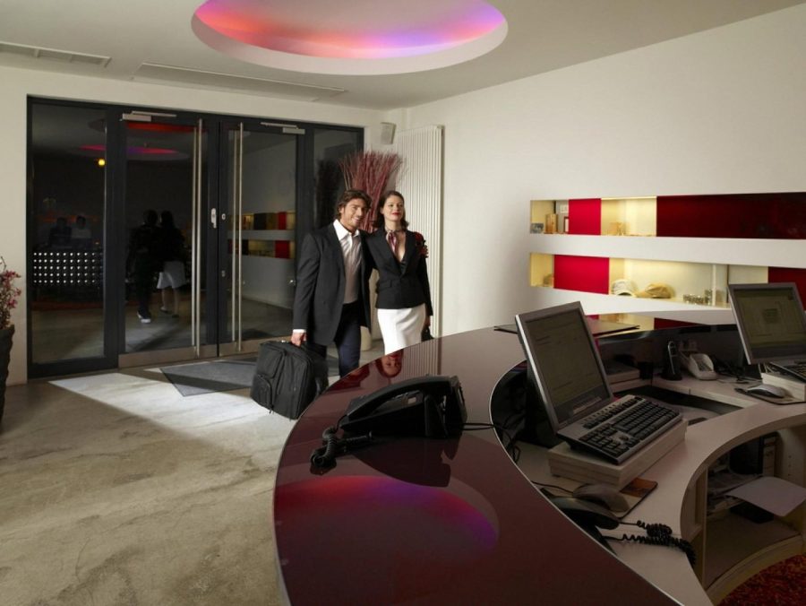 Couple with luggage arriving at a modern hotel reception desk at night