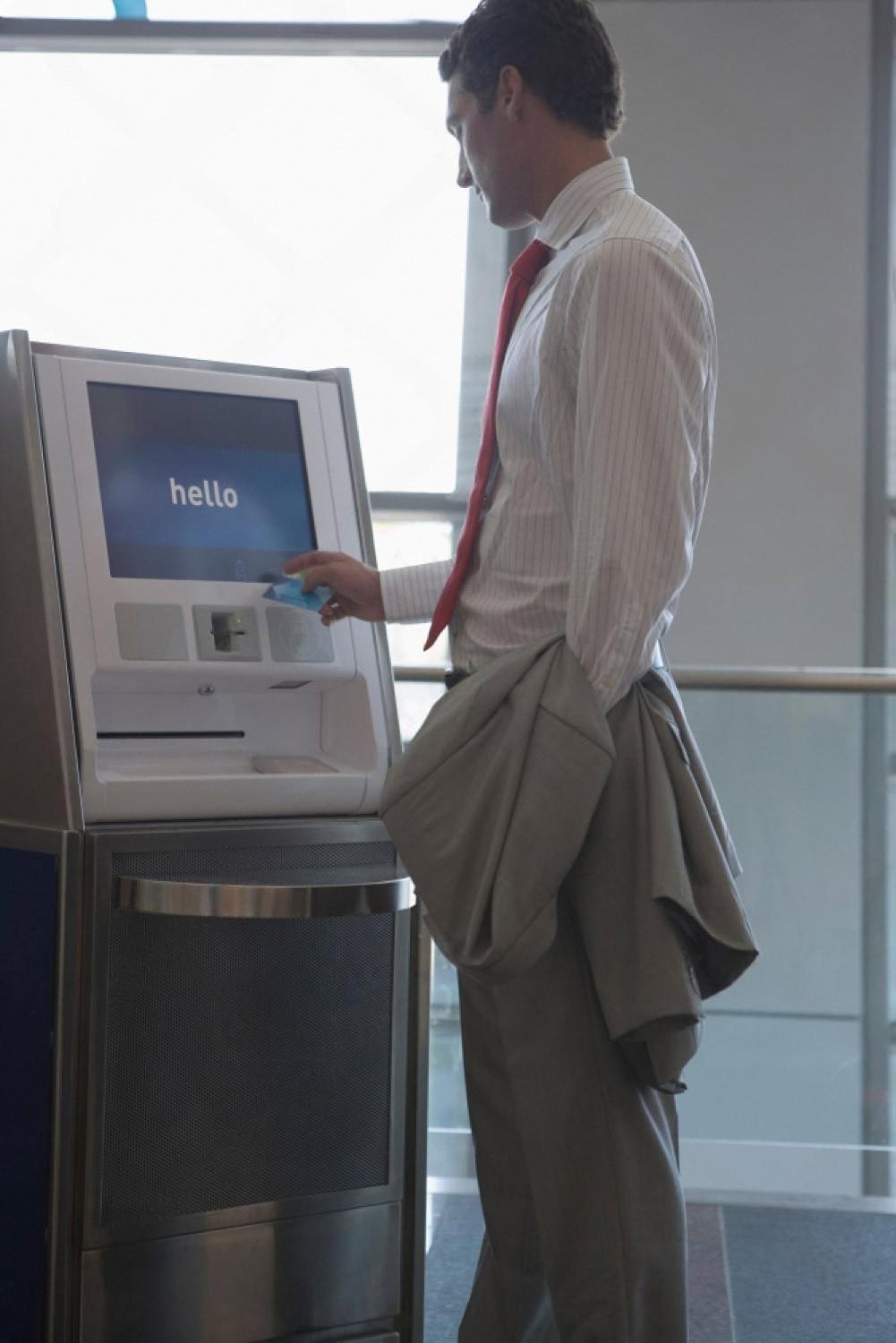 Business traveler using a self-service hotel check-in kiosk in an airport-style lobby